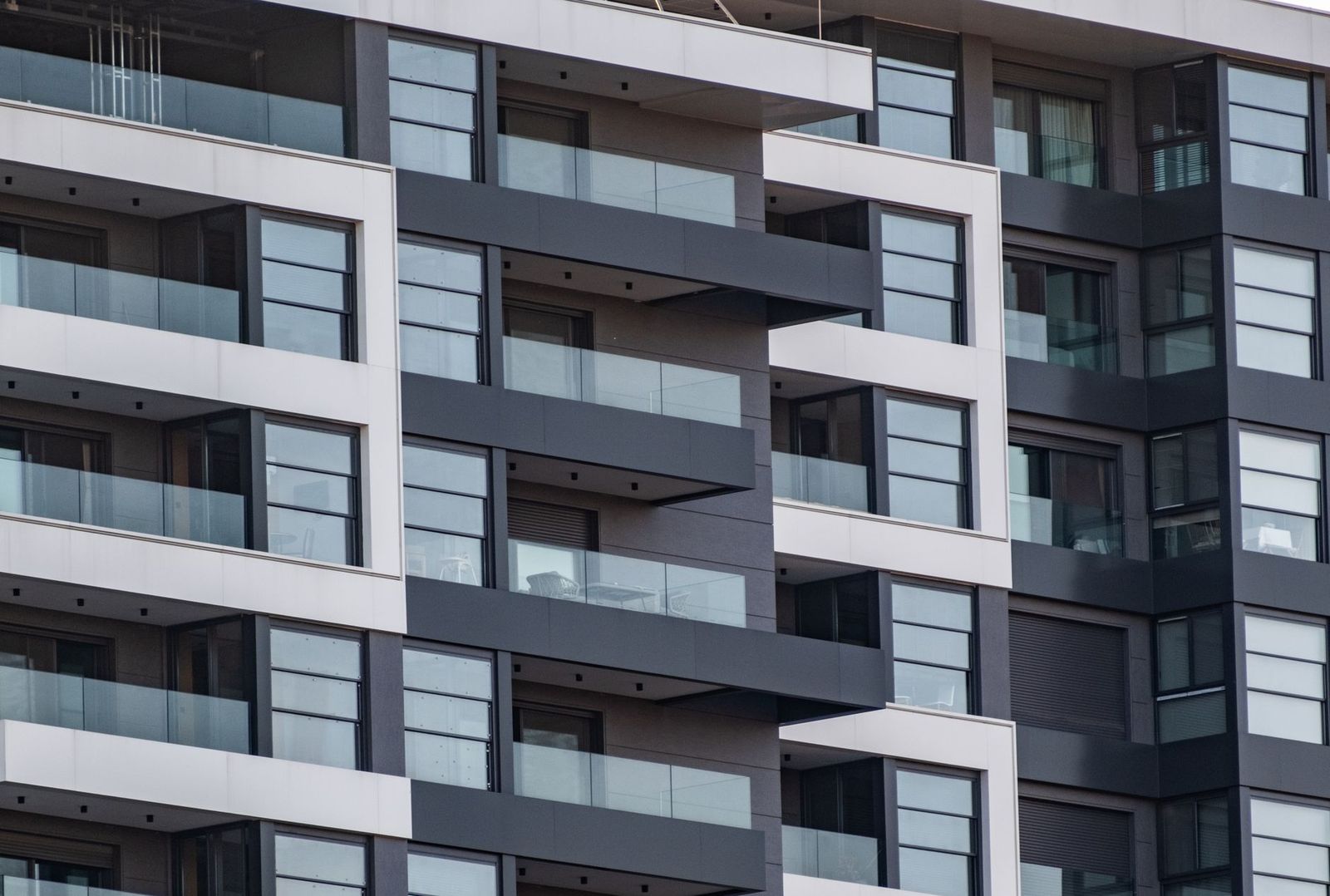 Rows of glass-railed balconies on a modern apartment building
