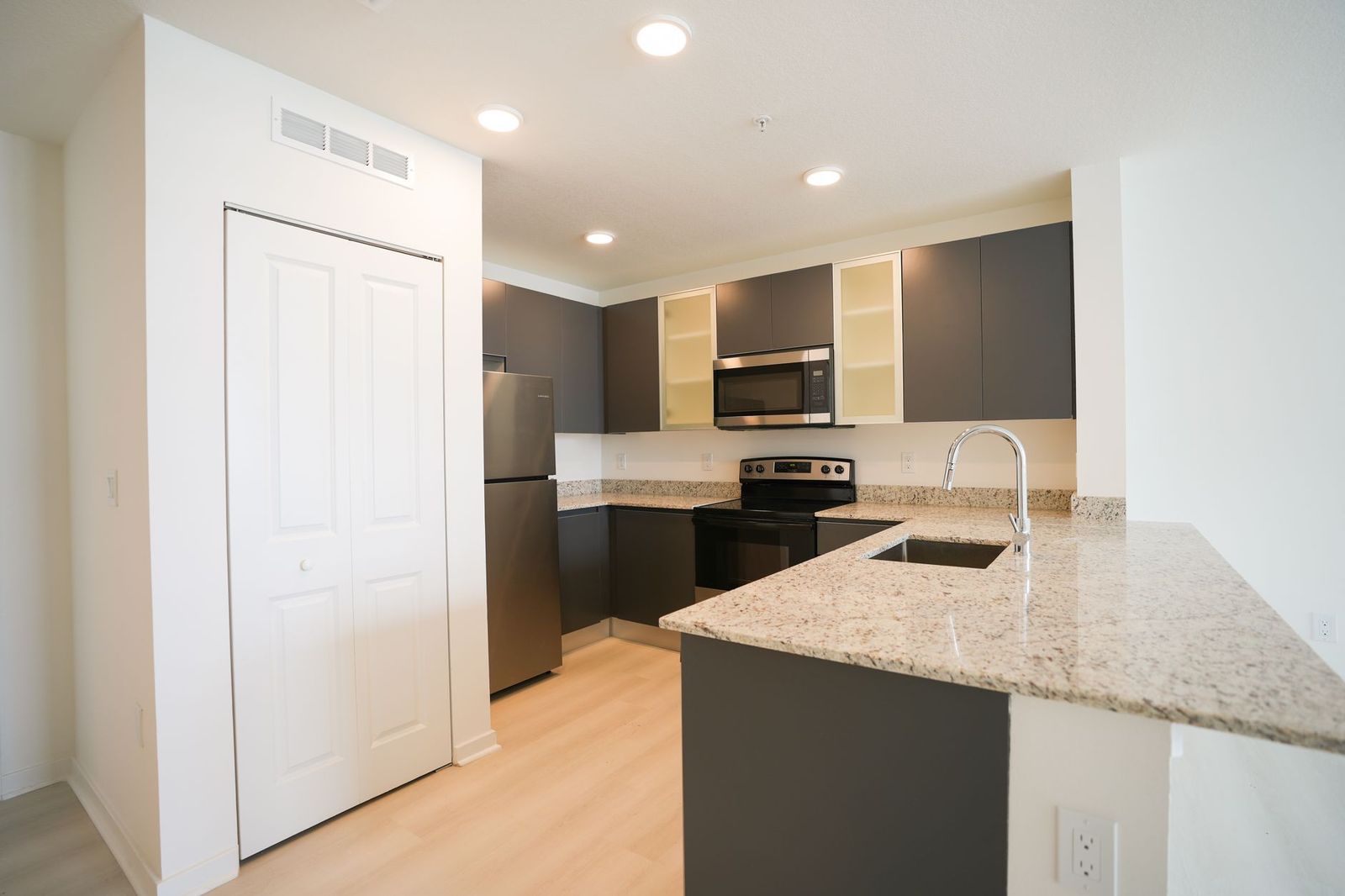 An apartment kitchen with granite counters, a breakfast bar and stainless appliances