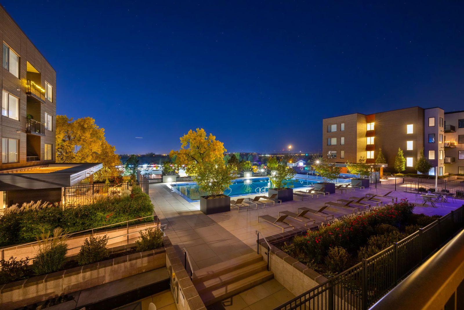 An apartment community courtyard and pool deck lit at dusk