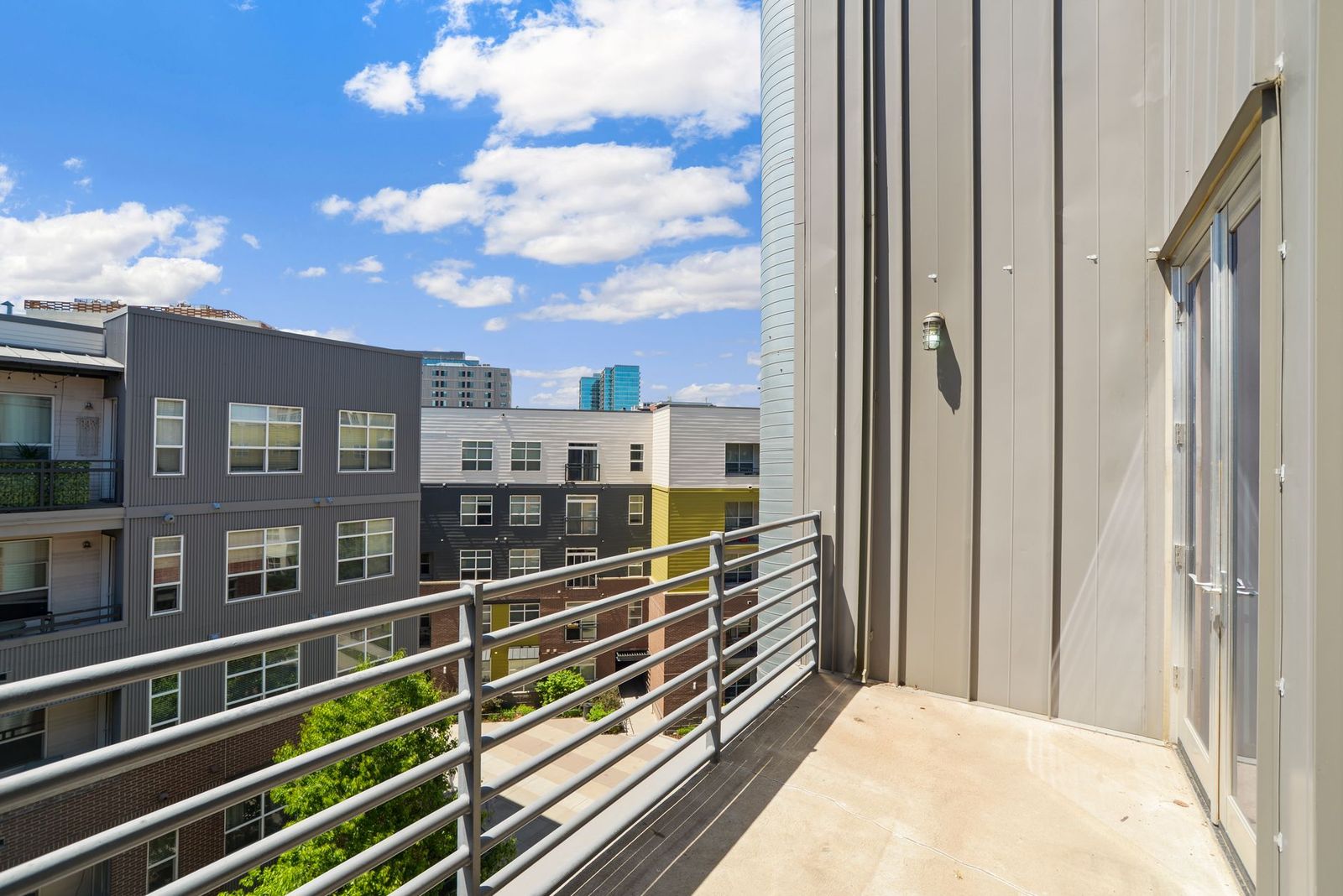 The view from an apartment balcony across a mid-rise courtyard toward a city skyline