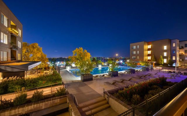 An apartment community courtyard and pool deck lit at dusk