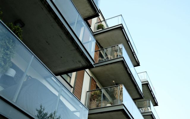 Tiers of glass-fronted apartment balconies planted with greenery