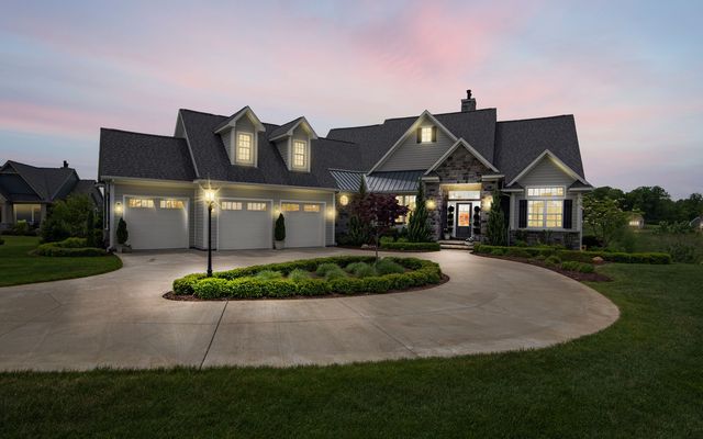 A large suburban house with a circular driveway lit at dusk