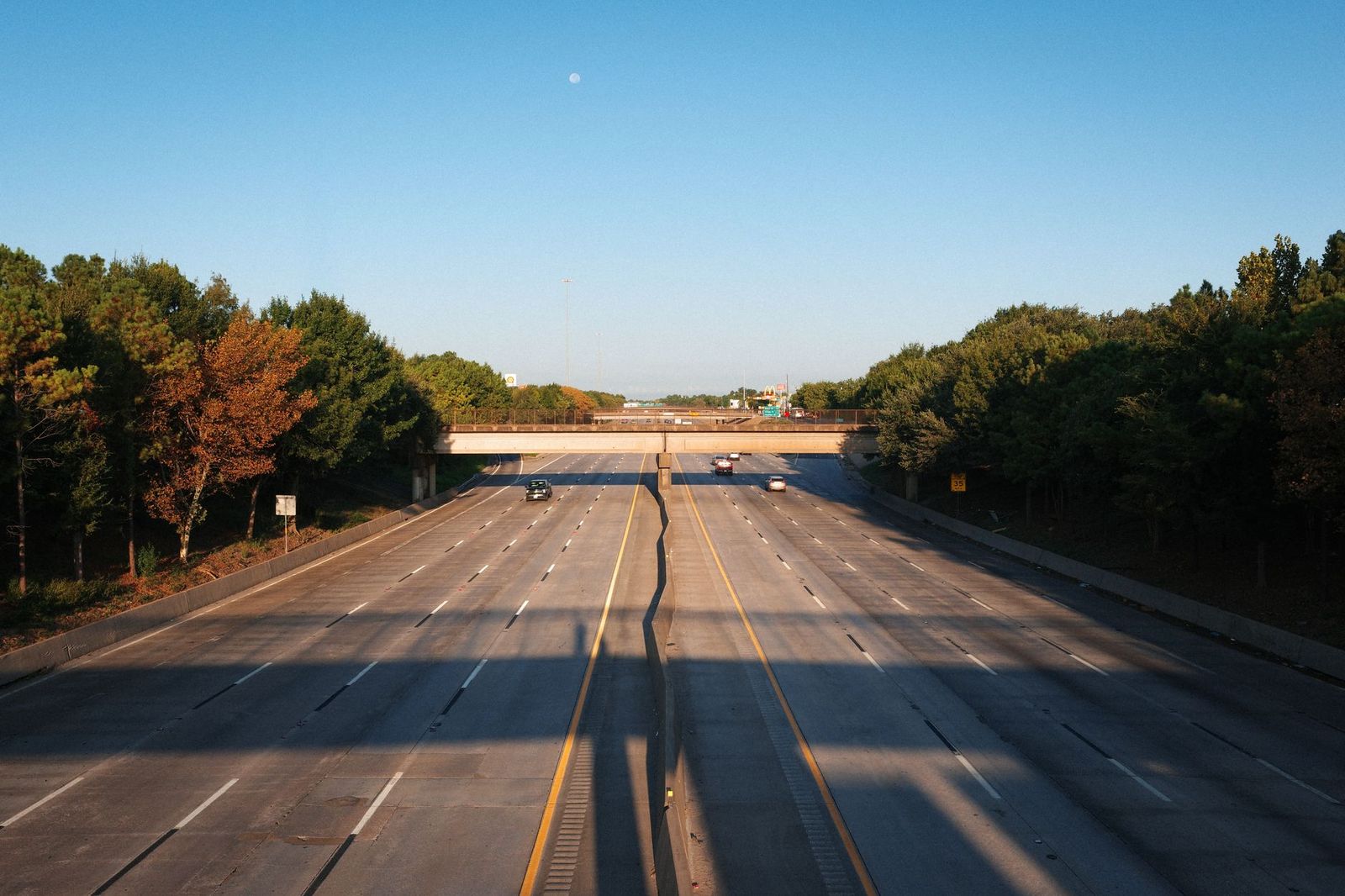 A wide freeway running under an overpass in early morning light