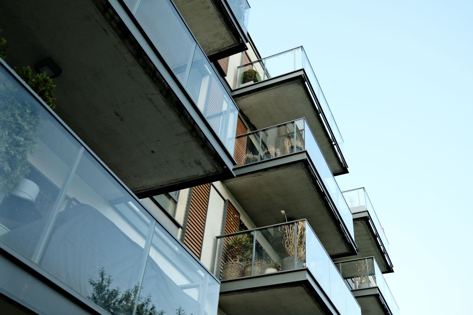 Tiers of glass-fronted apartment balconies planted with greenery