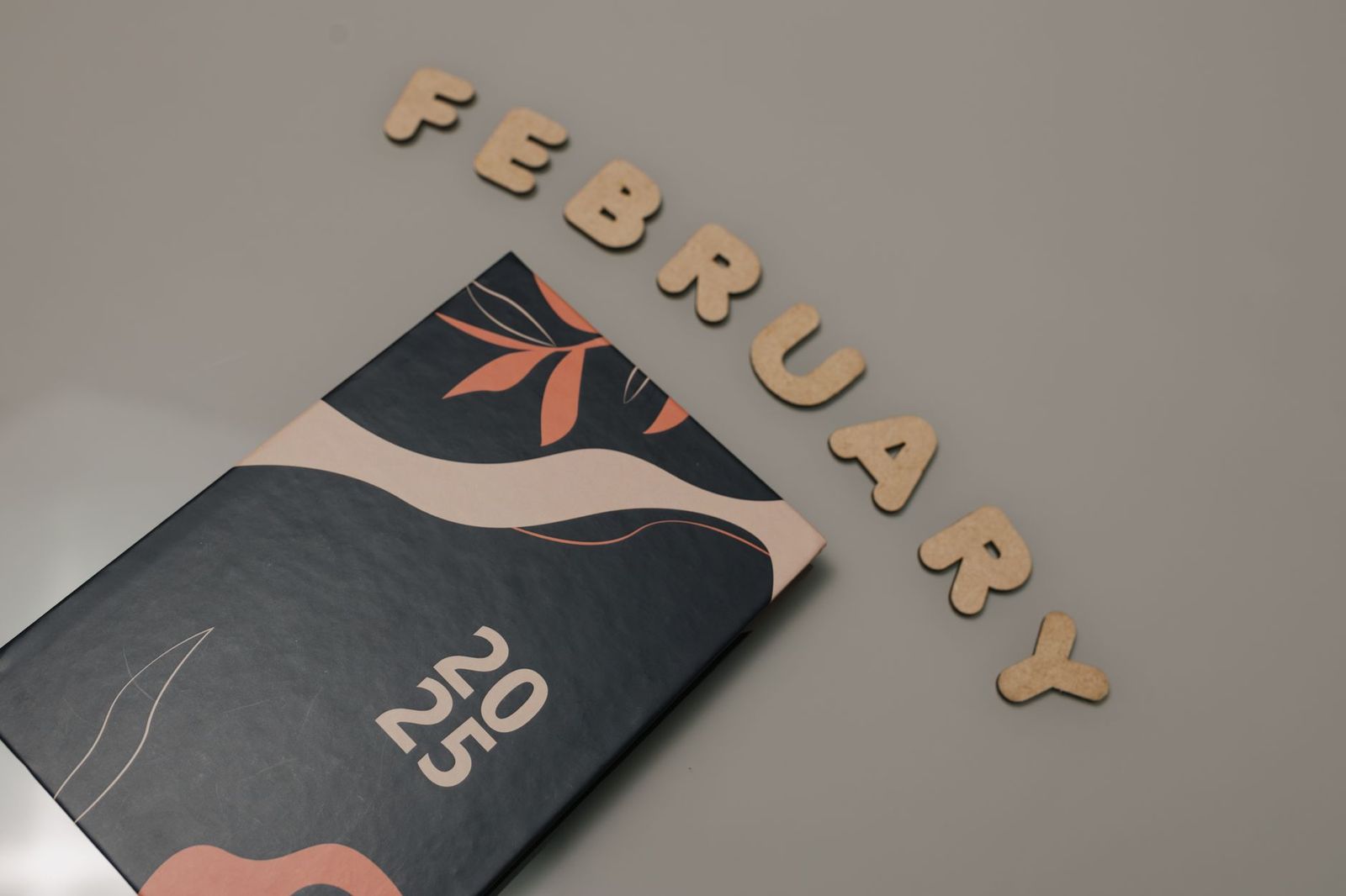 A monthly planner on a desk beside wooden letters spelling a month name