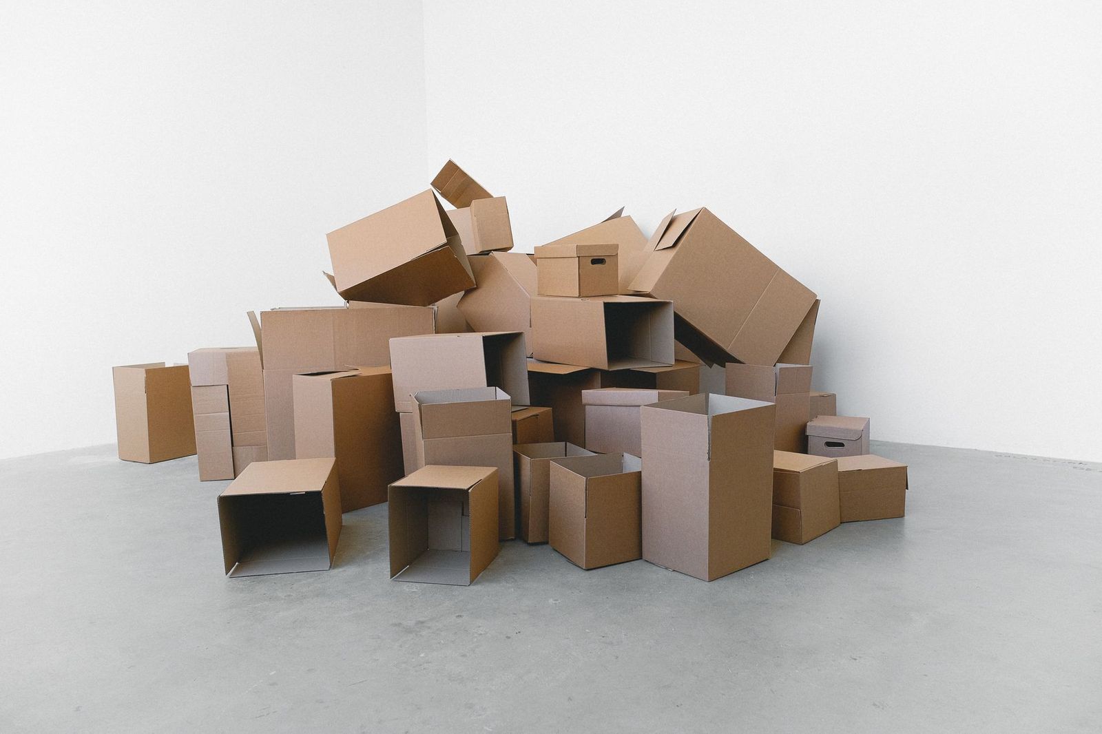 A pile of flattened and open cardboard moving boxes in an empty room