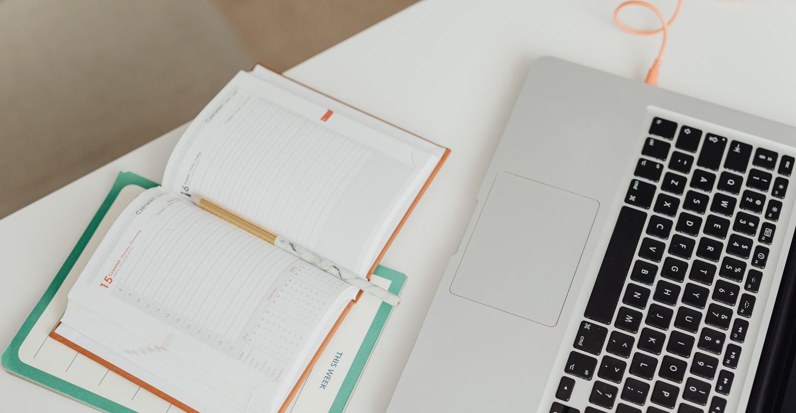 A week-view paper planner open on a desk next to a laptop