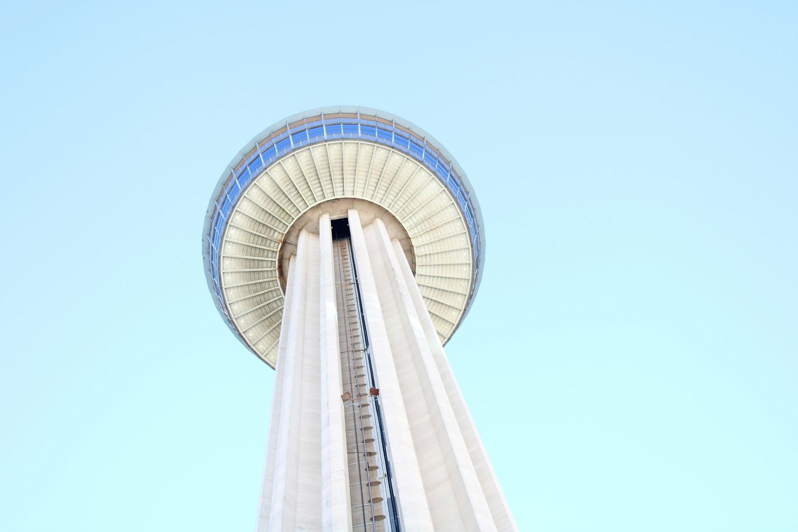 The observation deck of the Tower of the Americas seen from below against a clear sky